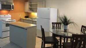 Une cuisine compacte dotée d’un îlot central, d’une table à manger avec des chaises et d’un réfrigérateur.