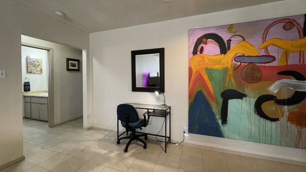 Une pièce comprenant un bureau, une chaise et un grand tableau abstrait accroché au mur.