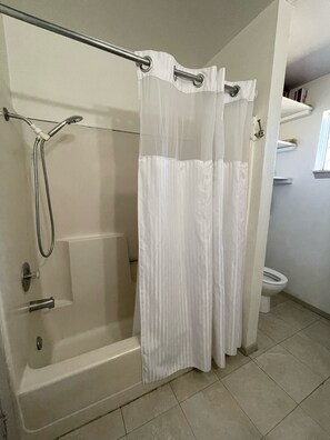 Een bad/douchecombinatie, een haardroger, handdoeken, toiletpapier