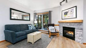 Ein modernes Wohnzimmer mit einer Couch, einem Couchtisch, einem Kamin und einem großen Fenster.