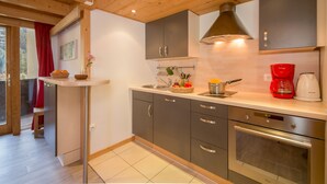 A modern kitchen with grey cabinets, a stainless steel oven, and a red coffee maker. - Grand Roc A218 150m from Slopes, View & Parking, Argentière (Chamonix), France (Argentière (Chamonix))