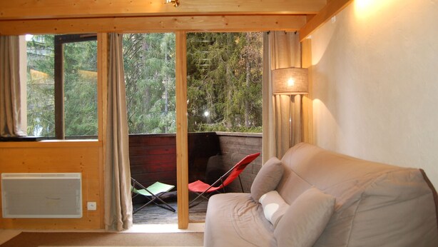 A cozy cabin interior with a sofa, a chair, and a large window offering a view of the forest. - Grand Roc A104 150m from Slopes, Parking & WiFi, Argentière (Chamonix), France (Argentière (Chamonix))