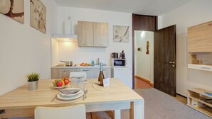Une cuisine moderne avec des meubles blancs, un four à micro-ondes et un coin repas avec une table mise pour deux personnes.