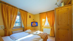A hotel room with a bed, a television, a wooden wardrobe, and yellow curtains. - Perla Ski in, Livigno, Italy (Livigno)