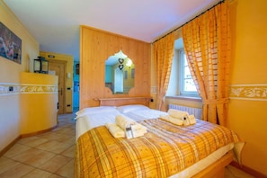A hotel room with a bed, a wooden headboard, a mirror, and a window with curtains.