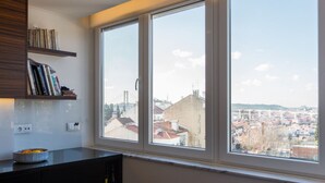 A modern kitchen with a large window, a built-in bookshelf, and a bowl of fruit on the counter. - Cozyplace 23 in Lisbon - 1 bedroom appartment (Lisboa)