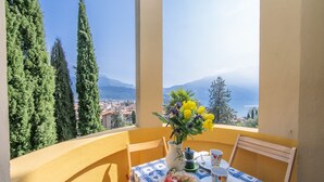 A balcony with a table set for two, overlooking a coastal town and mountains. - Appartamento Villa Lina with Lake View, Riva del Garda, Italy (Riva del Garda)