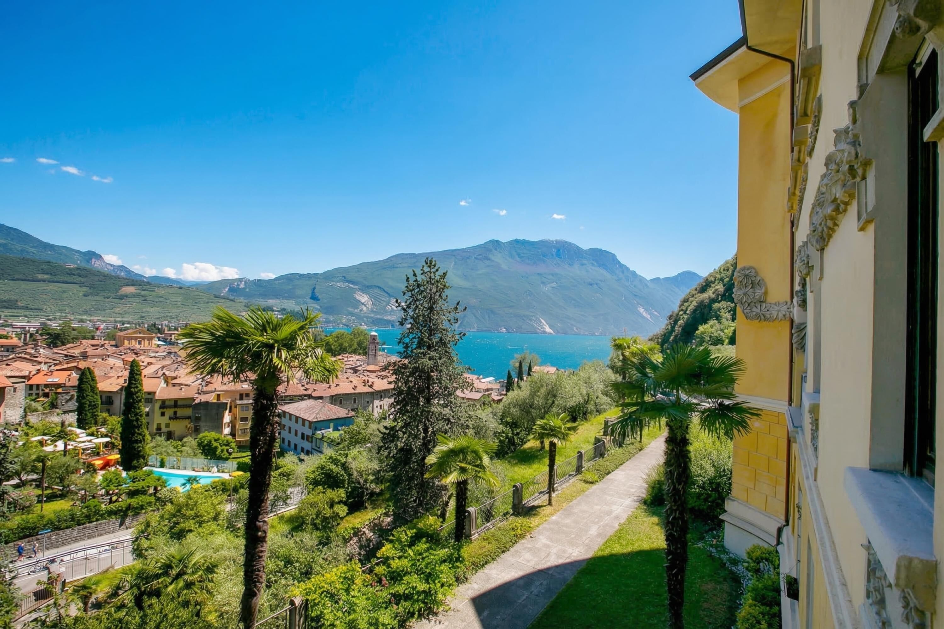 A view of a coastal town with a mountain in the background, a pathway leading to a building, and a clear blue sky.