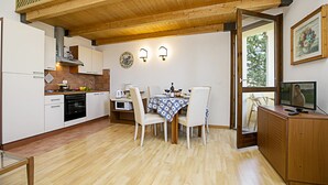 A modern kitchen with white cabinets, a wooden ceiling, and a dining area with a table set for four. - Appartamento Villa Lina with Lake View, Riva del Garda, Italy (Riva del Garda)