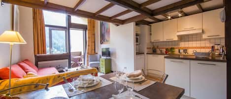 A dining area with a table set for four, a sofa, and a kitchen in the background.