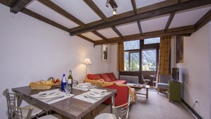 A dining area with a table set for two, a sofa, and a television. - Grand Roc B207 260m from Slopes, View, Parking & WiFi, Argentière (Chamonix), France (Argentière (Chamonix))