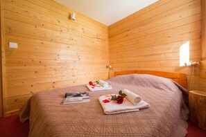Una habitación con paneles de madera, una cama, toallas y una pequeña mesa.