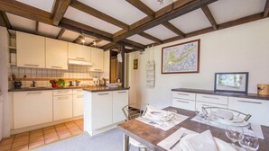 A kitchen with white cabinets, a wooden ceiling, and a dining area with a table set for four. - Grand Roc B207 260m from Slopes, View, Parking & WiFi, Argentière (Chamonix), France (Argentière (Chamonix))