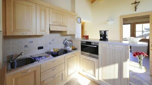A kitchen with wooden cabinets, a sink, a stove, and a coffee maker. - Arcobaleno, Livigno, Italy (Livigno)
