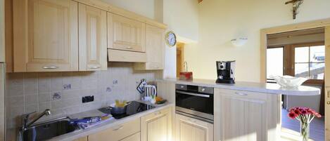 A kitchen with wooden cabinets, a sink, a stove, and a coffee maker.