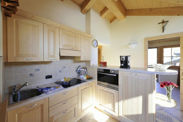 A kitchen with wooden cabinets, a sink, a stove, and a coffee maker. - Arcobaleno, Livigno, Italy (Livigno)