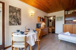 Un comedor con una mesa dispuesta para dos, un aparador de madera, una cama y una lámpara de pared.