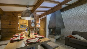 Ein gemütlicher Essbereich mit Holzwänden, einem Steinkamin und einem modernen Sofa.