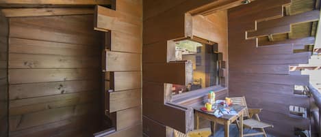 Une cabane en bois dotée d’un coin repas comprenant une table et des chaises.