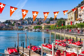Ein Yachthafen mit vertäuten roten Booten, im Hintergrund eine Stadtansicht und ein klarer, blauer Himmel.