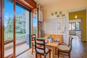 Un comedor con una mesa, sillas y vistas a árboles a través de un ventanal corredero.