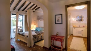 Un dormitorio con cama, una mesita, un espejo y vistas al exterior.
