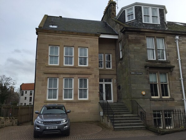 A two-story building with a stone facade, multiple windows, and a car parked in front. - 4 bedroom,5 bathroom,gamesroom, garden & parking, perfect for golf in St Andrews (st andrews)