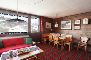 A cozy room with a wooden bench, a dining table, and a view of mountains through a window.
