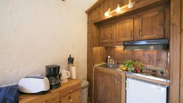 Une cuisine compacte avec des meubles de rangement en bois, un réfrigérateur Bosch, une machine à café et un grille-pain.