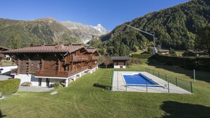 A wooden chalet with a swimming pool, surrounded by mountains. - Améthystes D12 Ski In/Ski Out w/Shared Pool in Argentière-Chamonix, Argentière (Chamonix), France (Argentière (Chamonix))