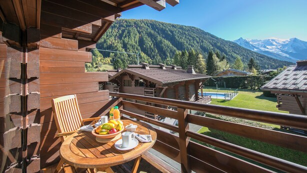 A wooden deck with a table set for breakfast, overlooking a mountainous landscape. - Améthystes D12 Ski In/Ski Out w/Shared Pool in Argentière-Chamonix, Argentière (Chamonix), France (Argentière (Chamonix))