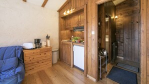 A compact kitchen with wooden cabinets, a built-in stove, and a small refrigerator. - Améthystes D12 Ski In/Ski Out w/Shared Pool in Argentière-Chamonix, Argentière (Chamonix), France (Argentière (Chamonix))