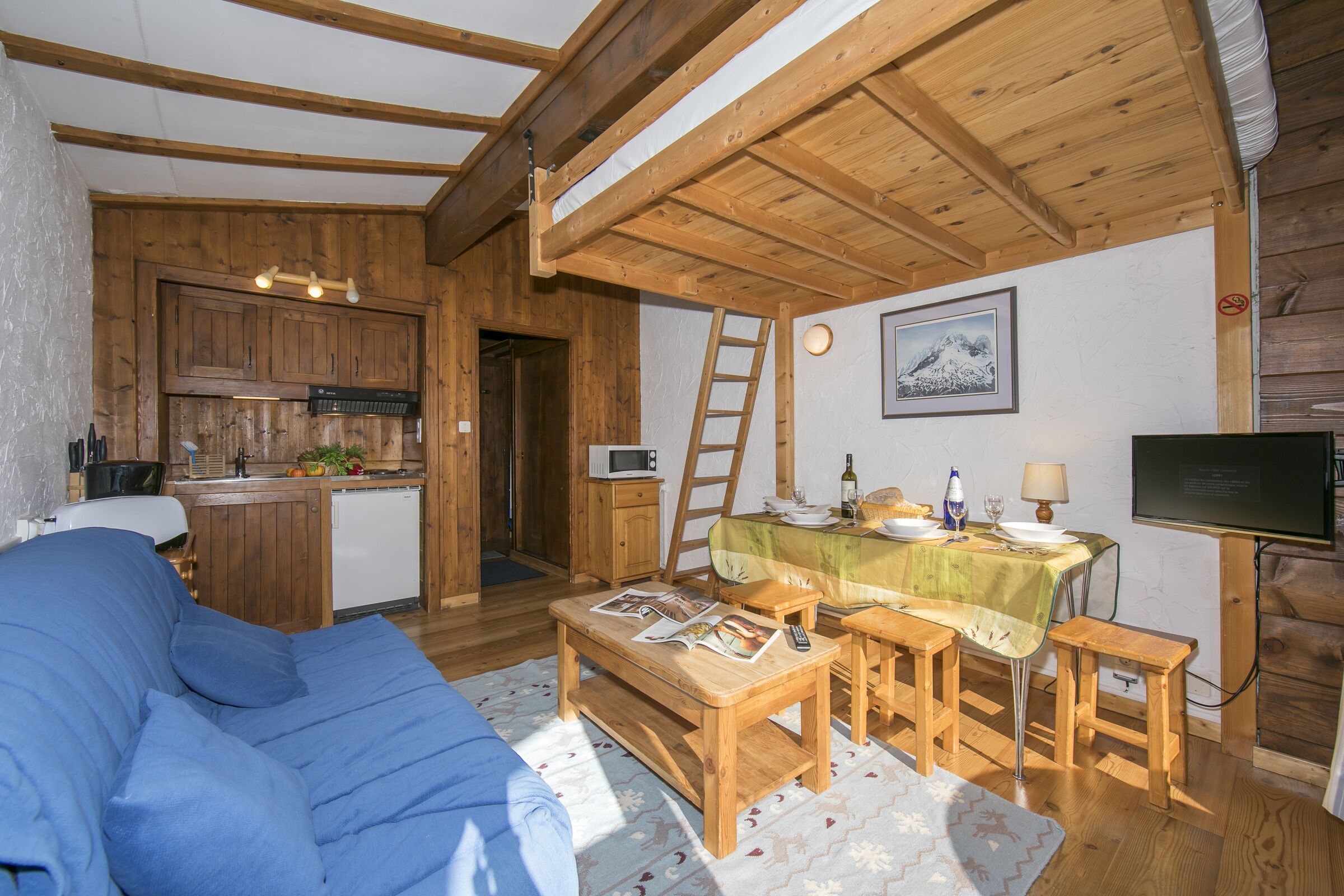 A cozy cabin interior with a living area, wooden dining table, and kitchen.