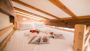 A wooden-framed attic bedroom with a bed, pillows, and a magazine. - Améthystes D12 Ski In/Ski Out w/Shared Pool in Argentière-Chamonix, Argentière (Chamonix), France (Argentière (Chamonix))