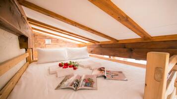 Een slaapkamer in de zolder met houten frame, een bed, kussens en een tijdschrift.