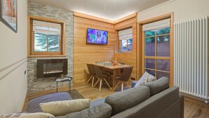 A cozy living room with a fireplace, a television, a dining area, and a large window. - Viola, Livigno, Italy (Livigno)