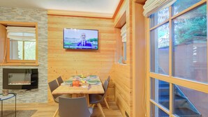 A wooden interior with a TV mounted on the wall, a dining table with chairs, and a fireplace. - Viola, Livigno, Italy (Livigno)