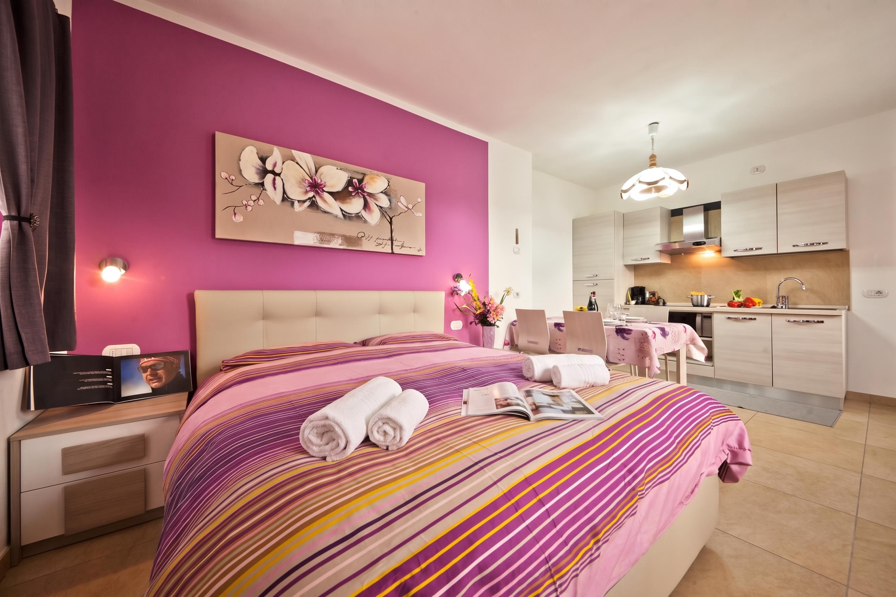Una habitación de hotel con cama, un cuadro, zona de comedor y cocina.