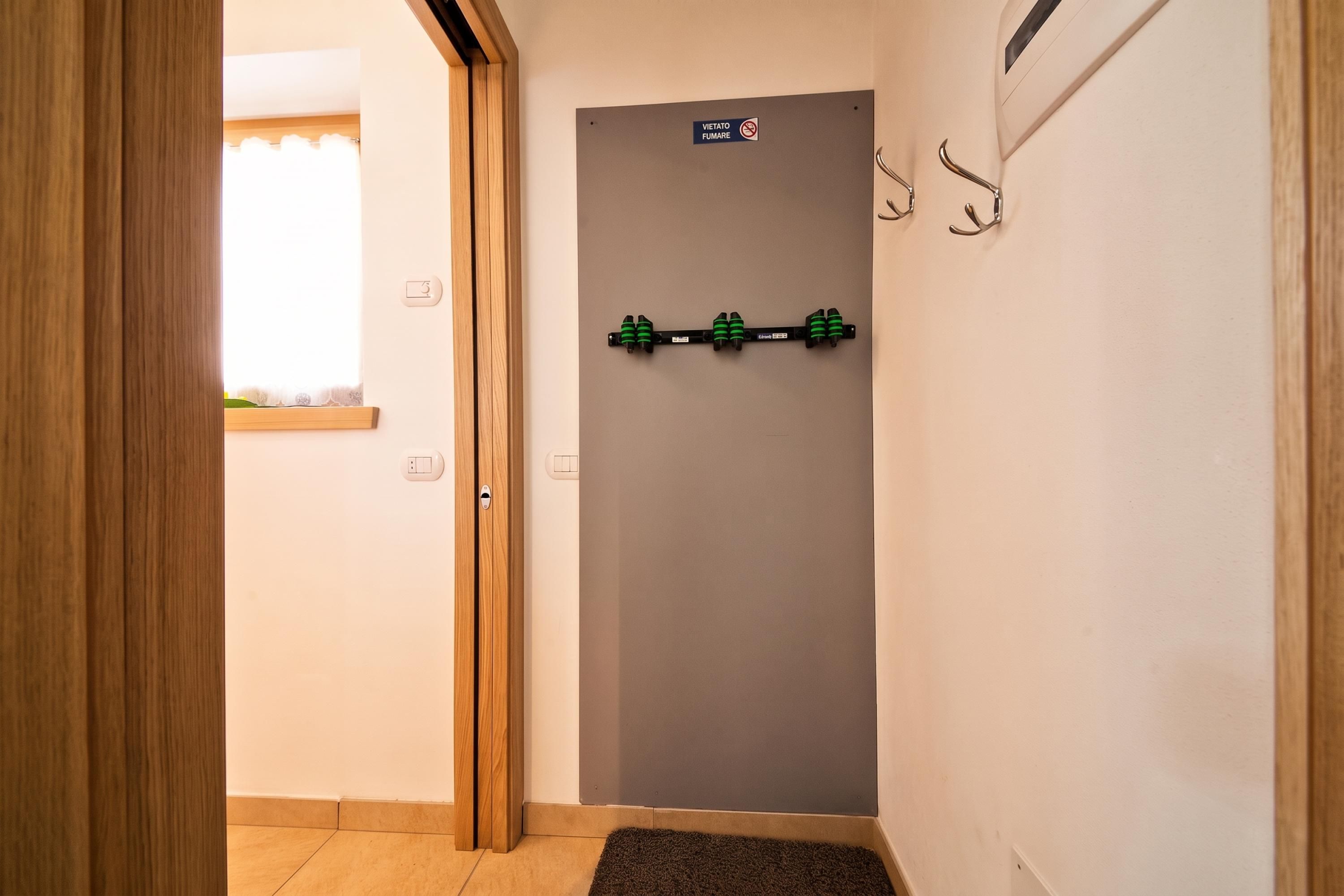 A hallway with a wooden door, a wall-mounted hook, and a small window with a curtain.