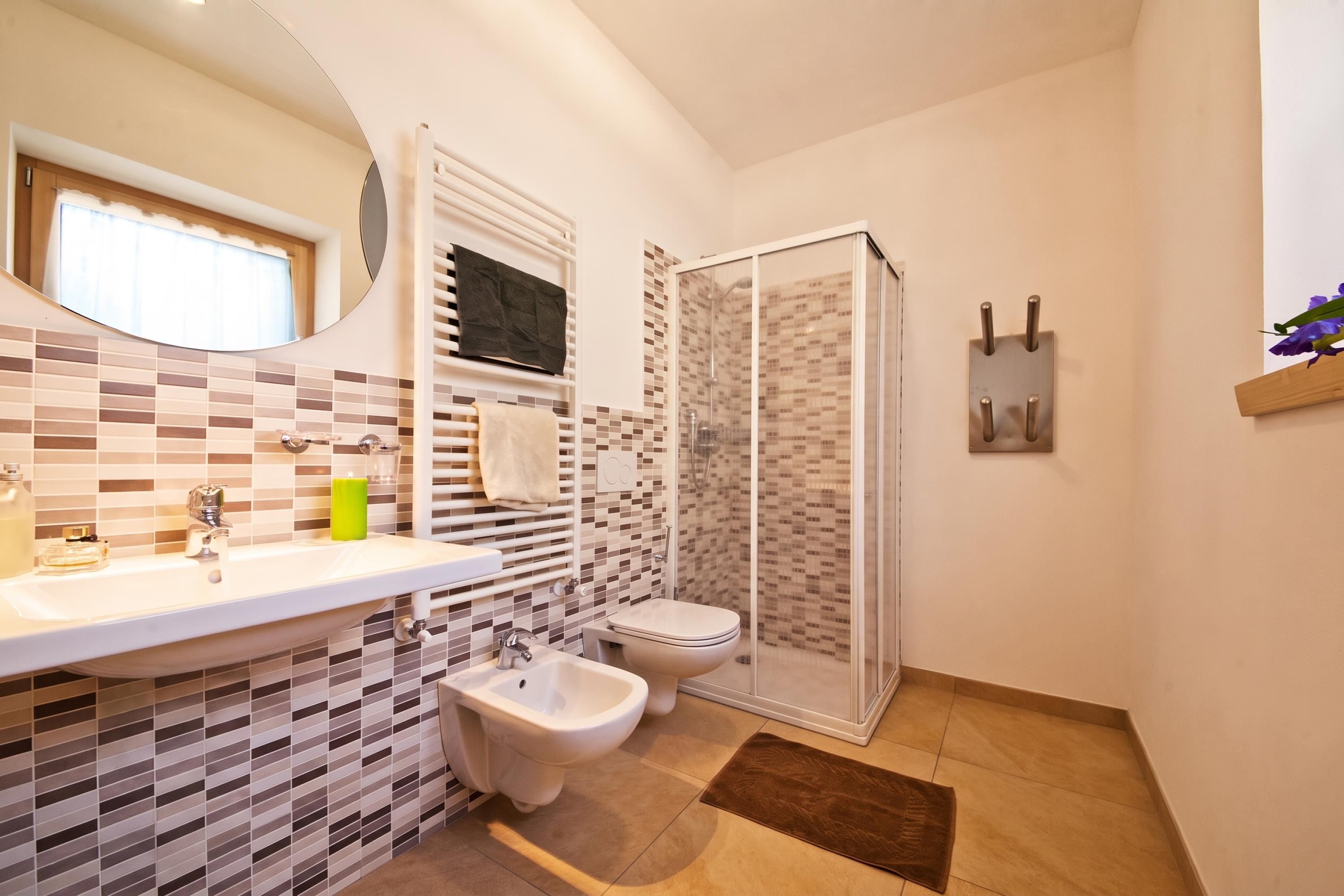 A bathroom with a bidet, a toilet, a sink, and a shower area.
