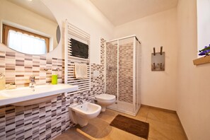 Un baño con bidé, inodoro, lavamanos y zona de ducha.