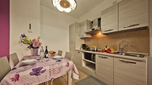 A modern kitchen with light wood cabinets, a stainless steel sink, and a dining area with a floral tablecloth. - Romantico, Livigno, Italy (Livigno)
