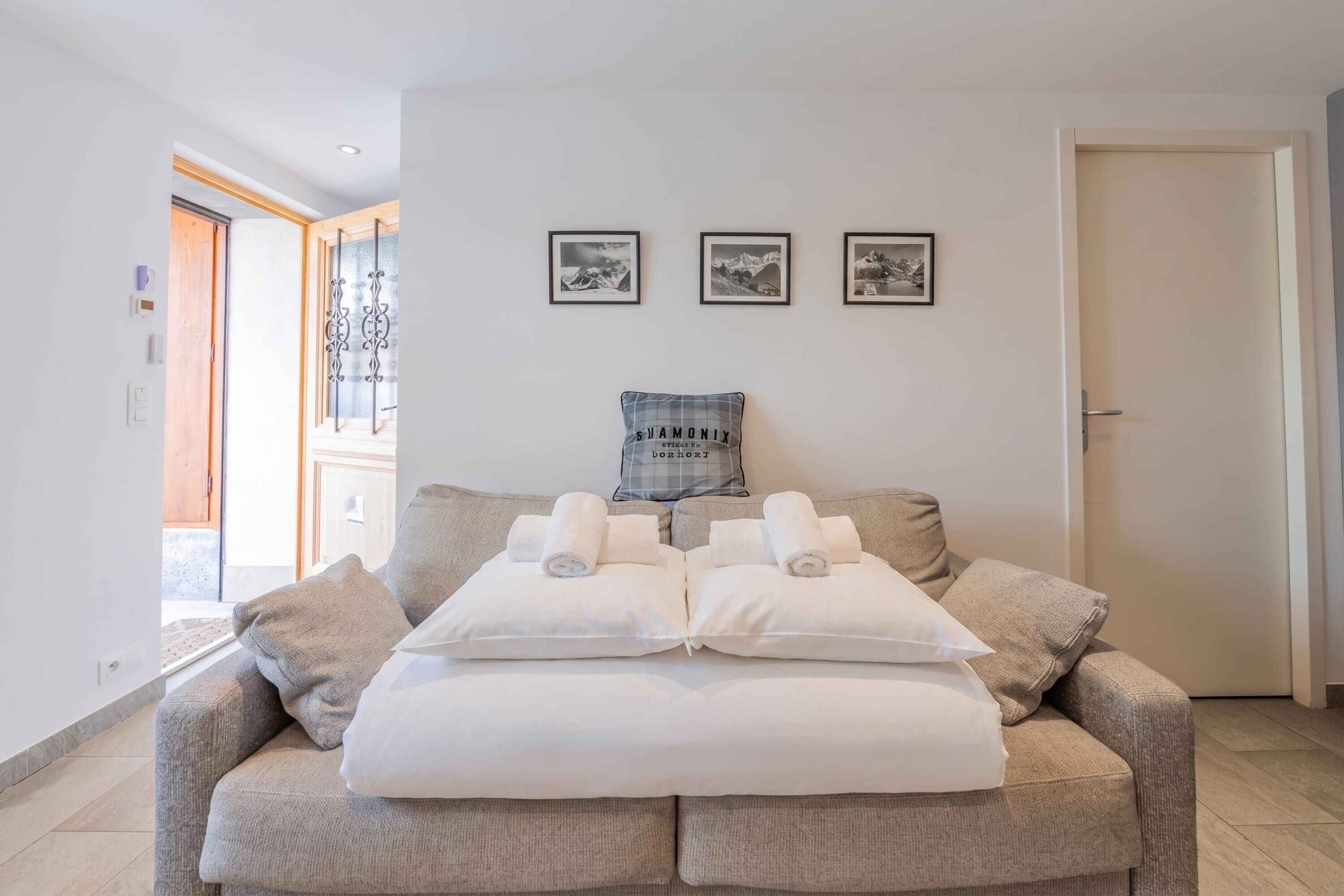 A cozy room with a sofa bed, a window with a view, and three framed pictures on the wall.