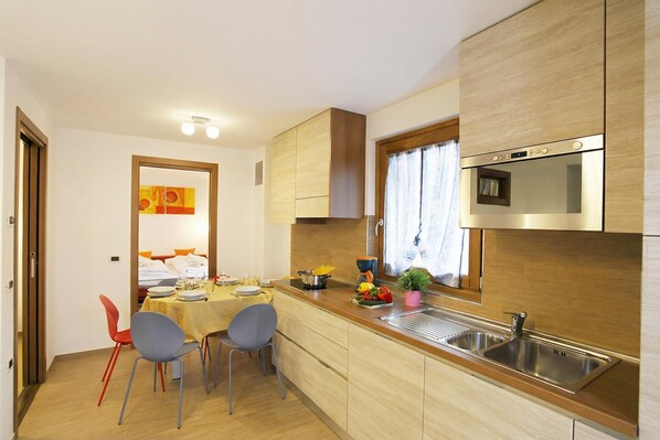 Una cucina compatta con mobili in legno, forno a incasso e lavandino.