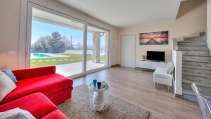 Ein geräumiges Wohnzimmer mit einem roten Sofa, einem Couchtisch, einem Fernseher und einer Treppe.
