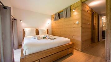 Een slaapkamer met houten lambrisering, een bed, gordijnen en een houten deur.