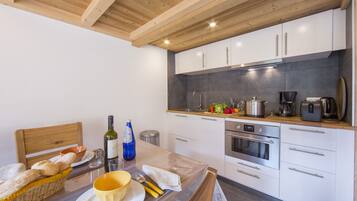 Een moderne keuken met witte kasten, een houten plafond en roestvrijstalen apparatuur.