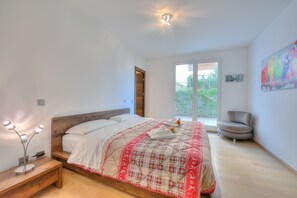 A bedroom with a bed, bedside table, and a chair.