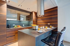 Une cuisine moderne dotée d’un îlot central, d’appareils électroménagers en acier inoxydable et d’un lambris mural en bois.