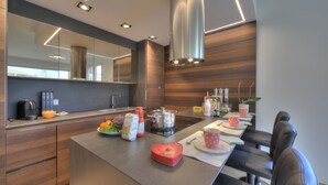 A modern kitchen with a central island, wooden paneling, and contemporary appliances. - Rebecca Garden with Terrace in Paradiso, Lugano, Switzerland (Lugano)